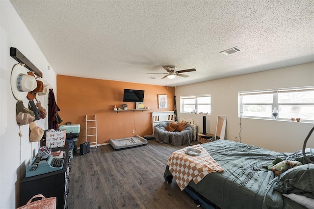 bedroom with a textured ceiling, wood finished floors, a ceiling fan, and visible vents