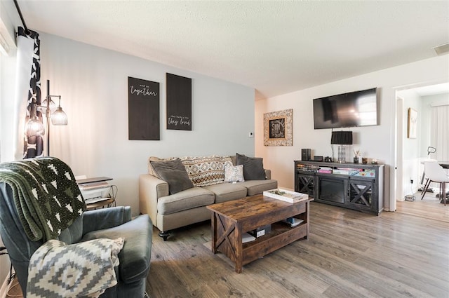 living room with visible vents, a textured ceiling, and wood finished floors