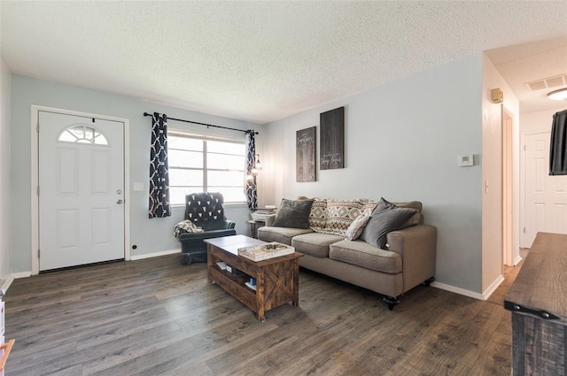 living room featuring visible vents, baseboards, a textured ceiling, and dark wood finished floors