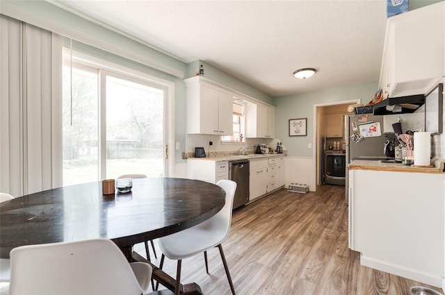dining space with light wood-style floors and a textured ceiling