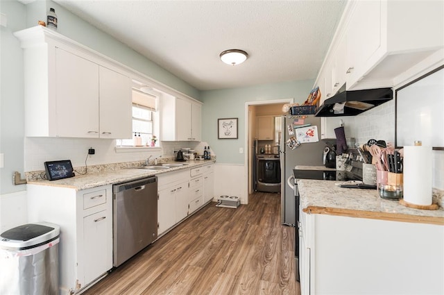 kitchen featuring light wood-style floors, stainless steel dishwasher, ventilation hood, and white cabinets