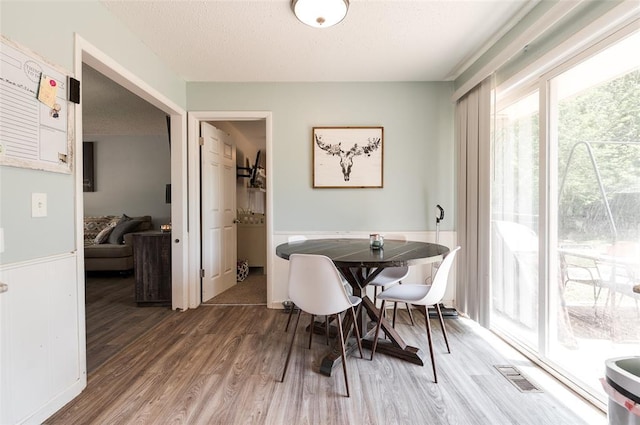 dining room with visible vents, wood finished floors, and a textured ceiling