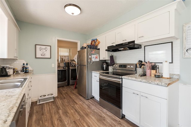 kitchen featuring dark wood finished floors, white cabinetry, appliances with stainless steel finishes, under cabinet range hood, and washer and dryer