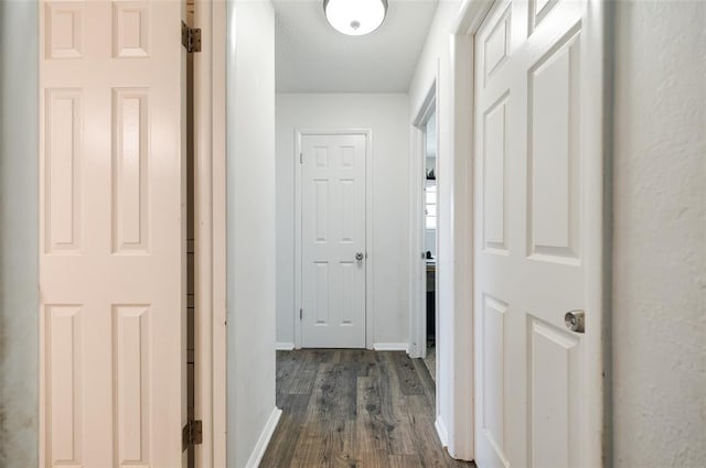 hall with dark wood-type flooring and baseboards