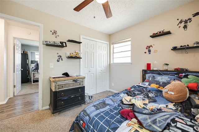 bedroom with a closet, ceiling fan, freestanding refrigerator, carpet, and a textured ceiling