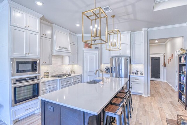9328 NW 118th St, Yukon, OK 73099 - kitchen featuring light countertops, premium range hood, white cabinetry, stainless steel appliances, and a sink