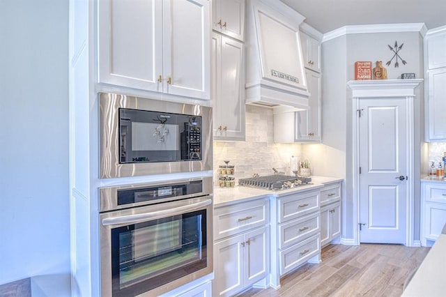 9328 NW 118th St, Yukon, OK 73099 - kitchen featuring custom range hood, light countertops, white cabinetry, crown molding, and stainless steel appliances