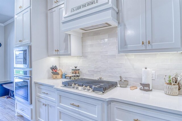 9328 NW 118th St, Yukon, OK 73099 - kitchen featuring stainless steel appliances, premium range hood, light countertops, and backsplash
