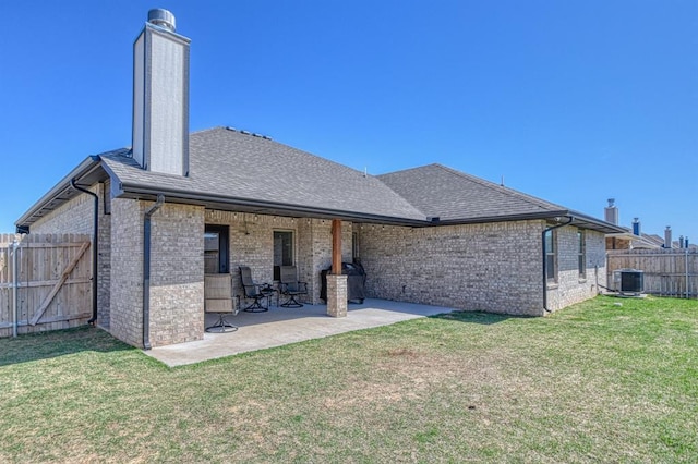 9328 NW 118th St, Yukon, OK 73099 - back of property featuring a chimney, a patio area, brick siding, a fenced backyard, and a lawn