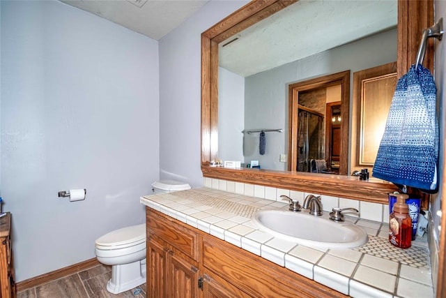 bathroom with vanity, baseboards, an enclosed shower, toilet, and wood finished floors