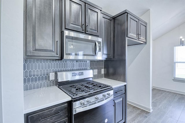 kitchen with stainless steel appliances, decorative backsplash, light countertops, and light wood-style flooring