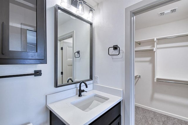bathroom with vanity, visible vents, and a walk in closet