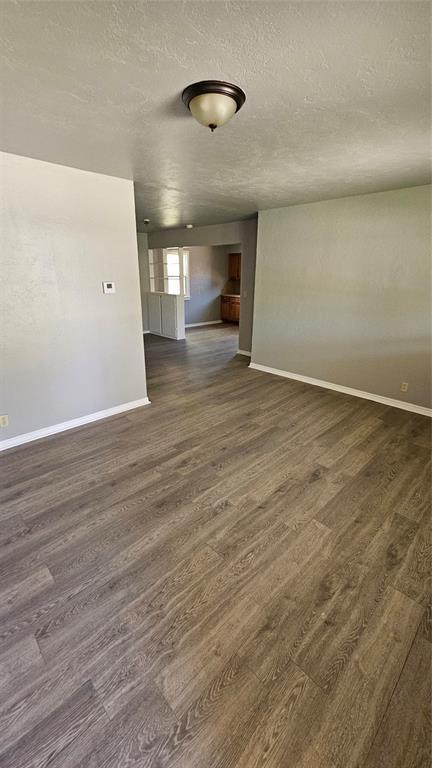 1708 NE 47th St, Oklahoma City, OK 73111 - unfurnished room featuring baseboards, a textured ceiling, and dark wood finished floors