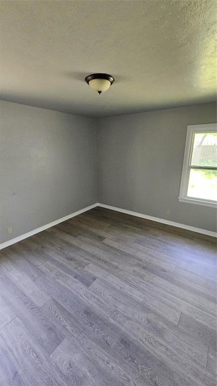1708 NE 47th St, Oklahoma City, OK 73111 - unfurnished room with baseboards, a textured ceiling, and dark wood-type flooring