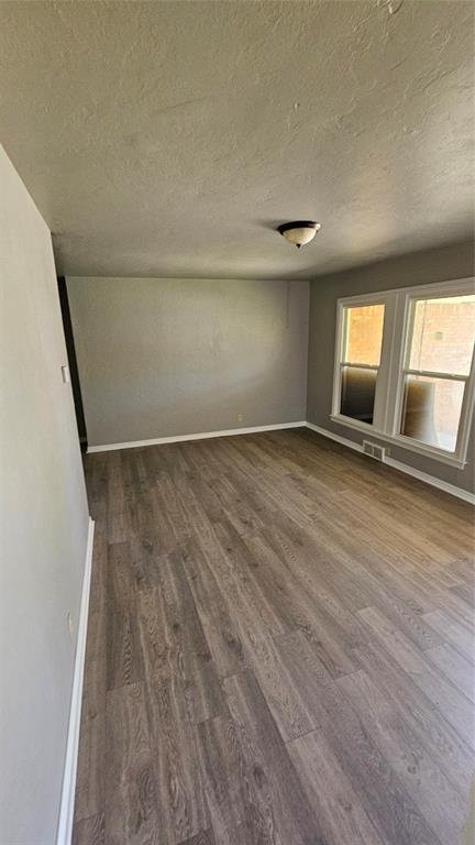 1708 NE 47th St, Oklahoma City, OK 73111 - unfurnished room with baseboards, visible vents, a textured ceiling, and dark wood-type flooring