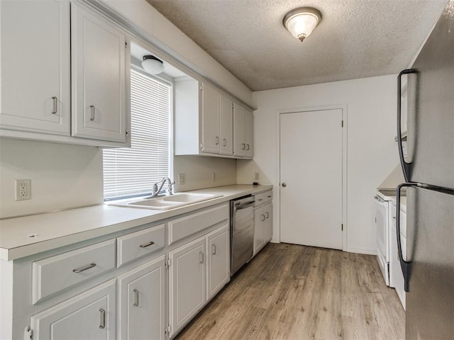 2416 Ellis Dr, Shawnee, OK 74804 - kitchen with a sink, freestanding refrigerator, a textured ceiling, light wood finished floors, and stainless steel dishwasher