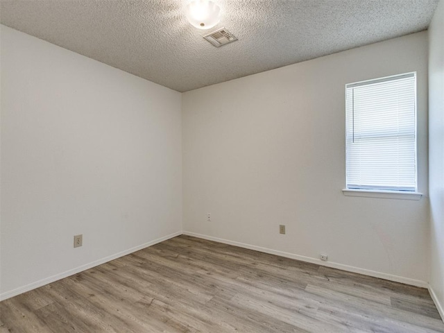 2416 Ellis Dr, Shawnee, OK 74804 - empty room with baseboards, visible vents, light wood-type flooring, and a textured ceiling