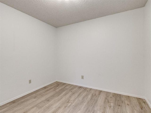 2416 Ellis Dr, Shawnee, OK 74804 - empty room featuring light wood-style flooring, baseboards, and a textured ceiling