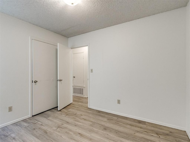 2416 Ellis Dr, Shawnee, OK 74804 - unfurnished bedroom with visible vents, light wood-style flooring, baseboards, and a textured ceiling