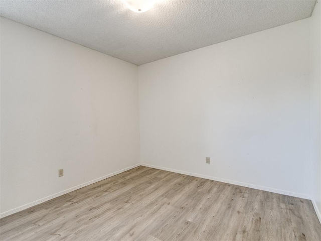 2416 Ellis Dr, Shawnee, OK 74804 - empty room with baseboards, light wood-type flooring, and a textured ceiling