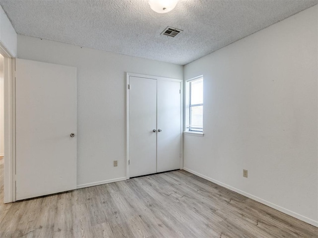 2416 Ellis Dr, Shawnee, OK 74804 - unfurnished bedroom featuring visible vents, a textured ceiling, baseboards, and wood finished floors