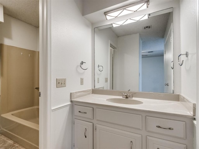 2416 Ellis Dr, Shawnee, OK 74804 - bathroom with tub / shower combination, a textured ceiling, vanity, visible vents, and wainscoting