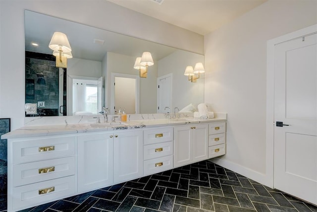bathroom featuring a shower stall, baseboards, a sink, and double vanity