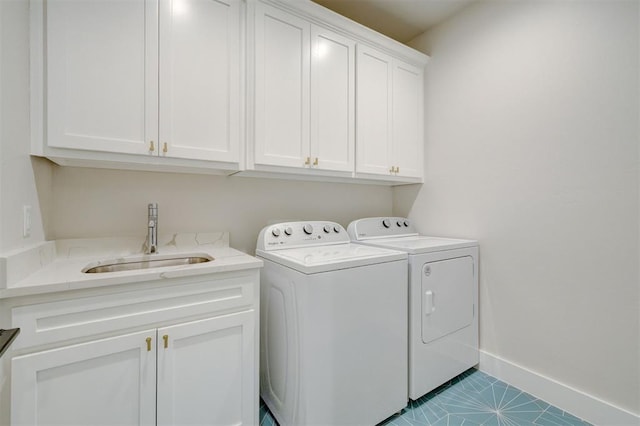 laundry room featuring cabinet space, washing machine and clothes dryer, baseboards, and a sink