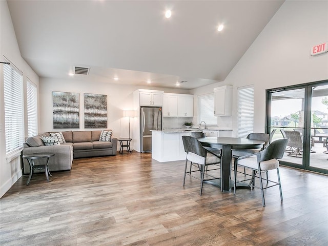 dining room featuring recessed lighting, light wood finished floors, visible vents, baseboards, and high vaulted ceiling