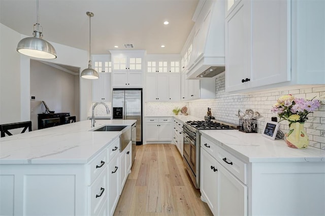 kitchen featuring custom exhaust hood, decorative backsplash, a kitchen island with sink, pendant lighting, and appliances with stainless steel finishes