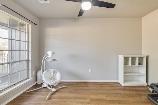 unfurnished room with a healthy amount of sunlight, wood finished floors, and a ceiling fan