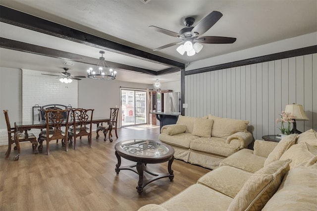 living room featuring beam ceiling, light wood finished floors, and ceiling fan with notable chandelier