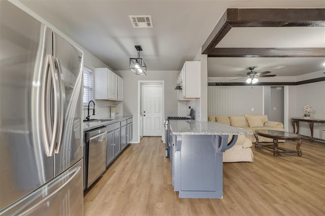 kitchen with light wood-style floors, visible vents, a kitchen bar, appliances with stainless steel finishes, and a sink