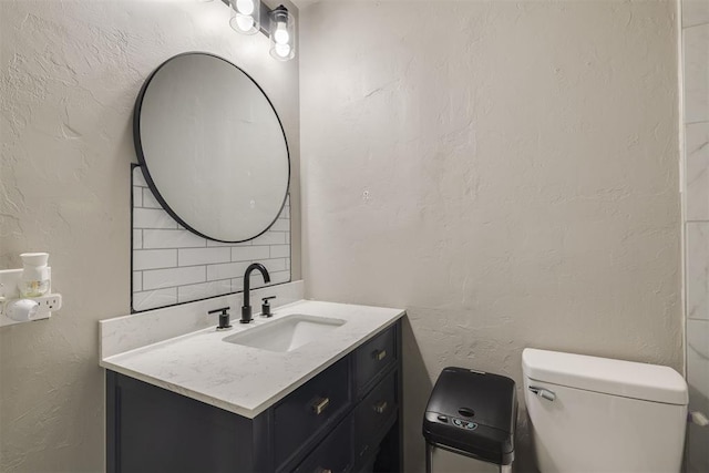 bathroom featuring vanity, toilet, and decorative backsplash