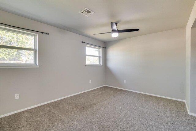 carpeted spare room with ceiling fan, baseboards, and visible vents