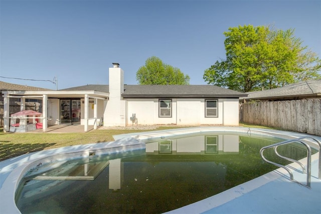 back of house featuring a patio area, fence, a fenced in pool, and a chimney