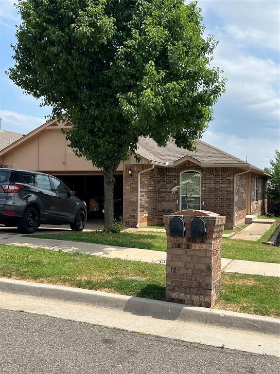 12308 SW 9th Ter, Yukon, OK 73099 - view of front facade with an attached garage, brick siding, a shingled roof, and driveway