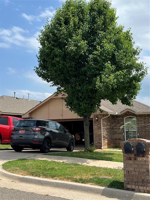 12308 SW 9th Ter, Yukon, OK 73099 - view of front of home with roof with shingles, brick siding, concrete driveway, and an attached garage