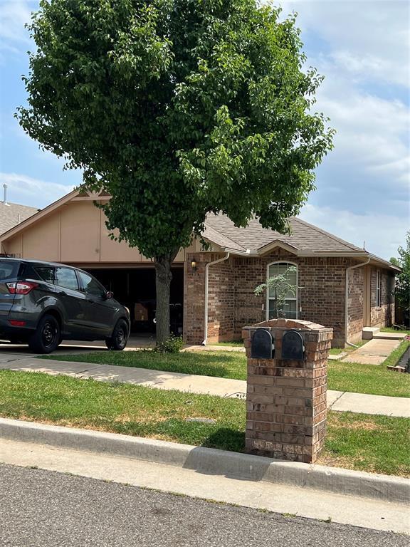 12308 SW 9th Ter, Yukon, OK 73099 - view of front of house featuring a garage, brick siding, roof with shingles, and driveway