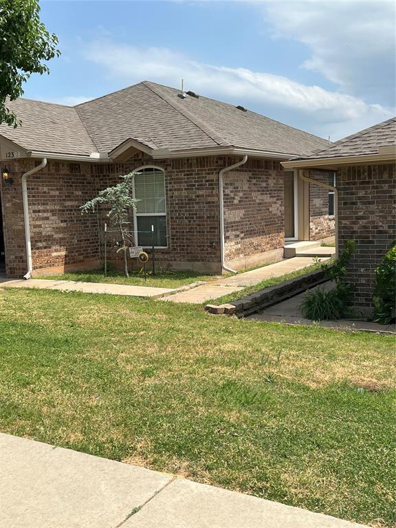 12308 SW 9th Ter, Yukon, OK 73099 - view of home's exterior featuring brick siding, a yard, and a shingled roof