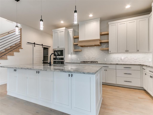 3532 Paso Robles Ter, Edmond, OK 73034 - kitchen with light wood-style floors, open shelves, a kitchen island with sink, custom range hood, and built in microwave