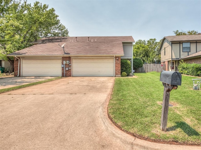 view of front facade featuring a front yard, fence, brick siding, an attached garage, and concrete driveway