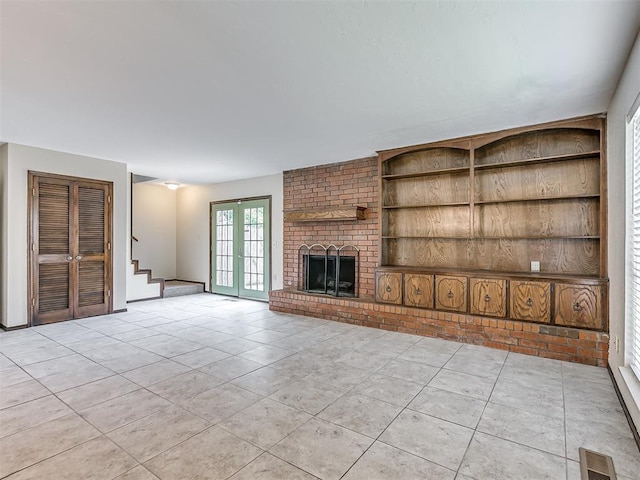 unfurnished living room with light tile patterned flooring, stairs, a brick fireplace, visible vents, and built in shelves
