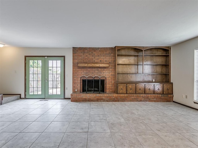 unfurnished living room featuring french doors, light tile patterned flooring, a fireplace, and built in shelves