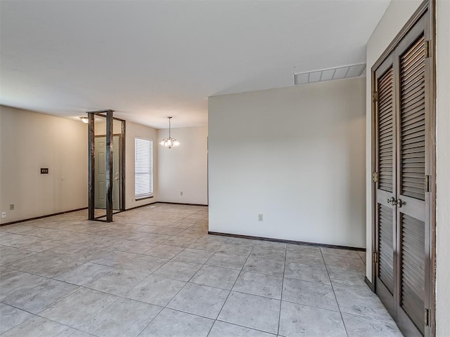 empty room with visible vents, baseboards, and an inviting chandelier