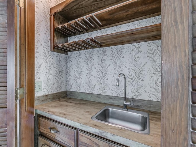 kitchen featuring a sink, light countertops, and wallpapered walls