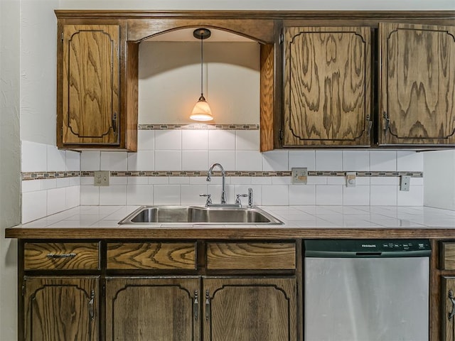 kitchen with tile counters, decorative backsplash, dishwasher, a sink, and hanging light fixtures
