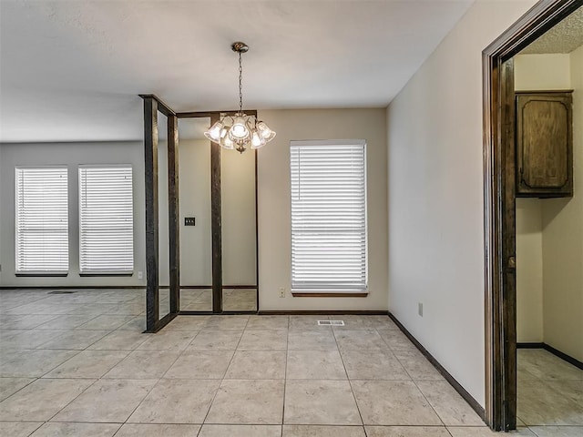 unfurnished dining area with baseboards, an inviting chandelier, and light tile patterned flooring