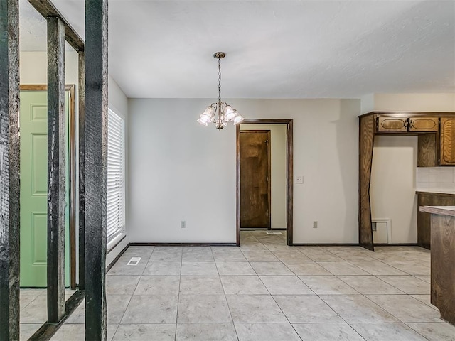 unfurnished dining area featuring an inviting chandelier, baseboards, and light tile patterned floors