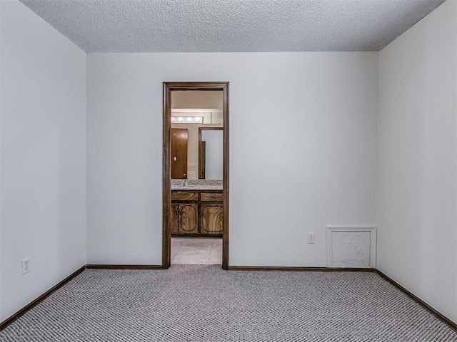 empty room featuring baseboards, light colored carpet, and a textured ceiling